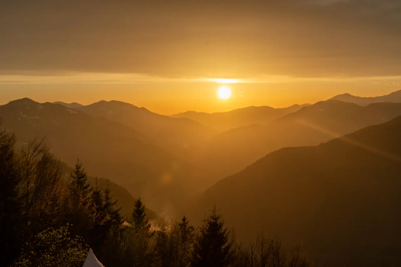 The sun setting over layered mountain ridges, with the whole valley glowing gold.